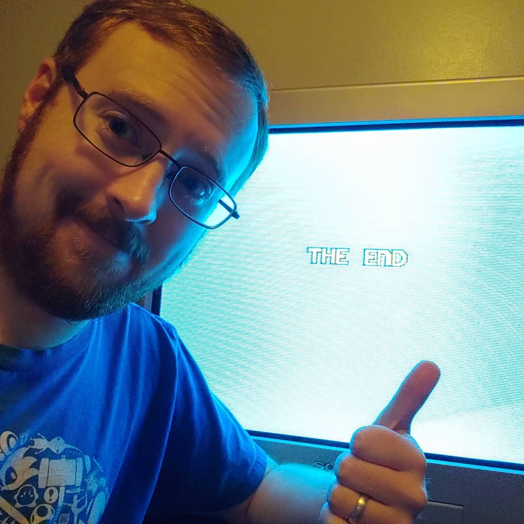 A photo of Tylor in front of a CRT displaying the end sreen of Adventures of Lolo for the NES