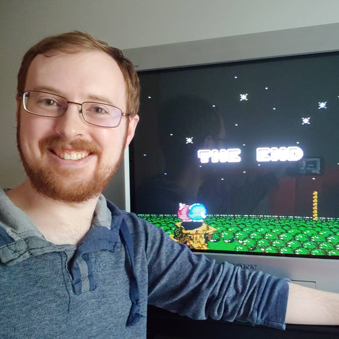 A photo of Tylor in front of a CRT displaying the end screen of Adventures of Lolo 2 for the NES